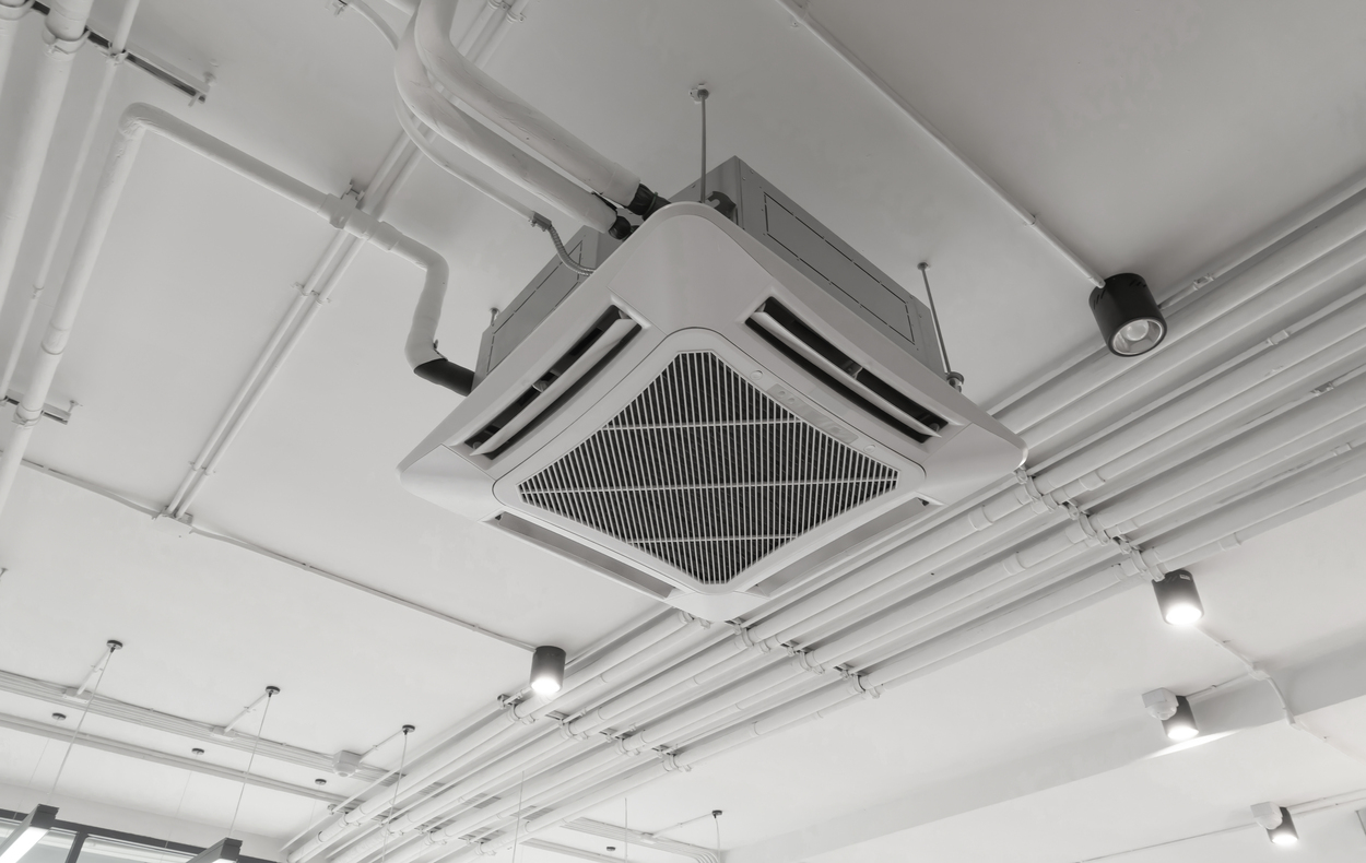 Modern white ceiling mounted cassette type air conditioner in office building system work. Ventilation compressor.